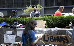 Police watch over protesters at a park near the Wall Street in New York, the United States, on Sept. 27, 2011. After several streets around the Wall Street have been blockaded since Sept. 16, protesters pitched their tents at the Bowling Green and Battery Park to continue their demonstration.